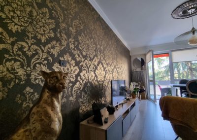 Un salon décoré à l'aide de papier peint baroque noir et doré.