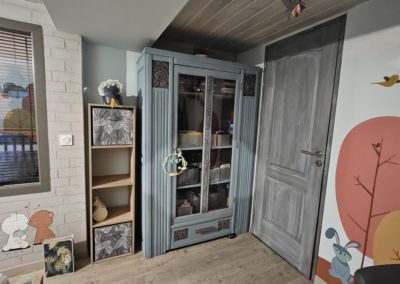 photo prise à gauche de la chambre d'un bébé complètement réaménagée. Peinture écologique et illustration à main levé.