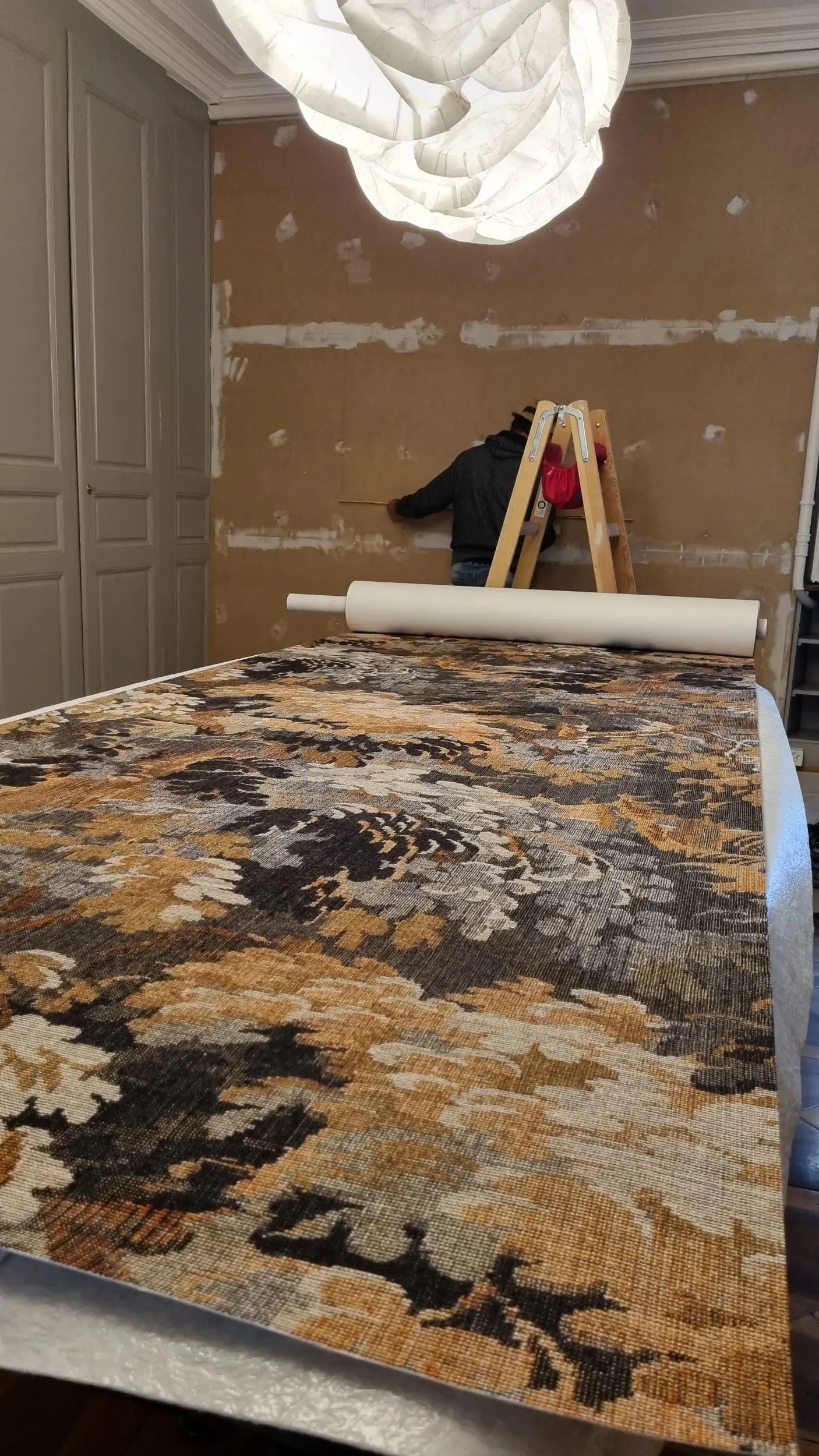 Préparation pour la pose d'un revêtement mural textile haut de gamme, imprimé végétal.